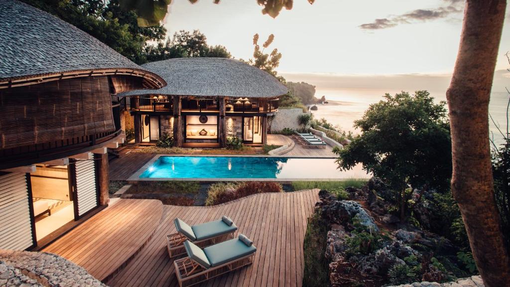Eco-luxury villas at Suarga Padang Padang in Uluwatu featuring a private pool, wooden architecture, tropical surroundings, and ocean views at sunset.