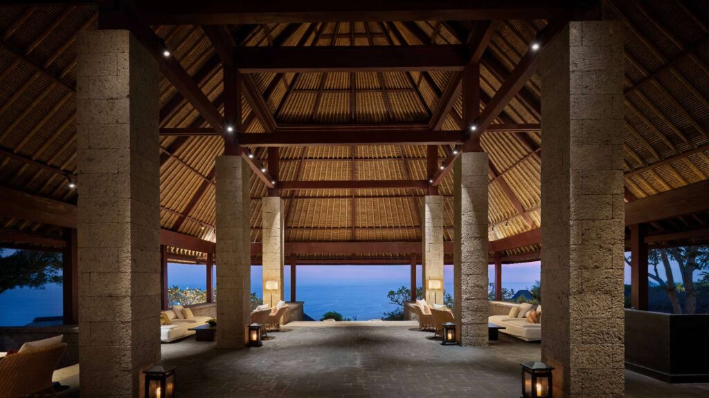 Top resorts in Uluwatu - Open-air pavilion at Bulgari Resort Bali in Uluwatu featuring traditional Balinese architecture, stone pillars, and ocean views at sunset.