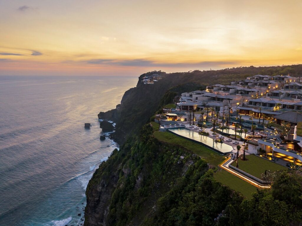 Aerial sunset view of Six Senses Uluwatu resort in Bali featuring luxury cliffside villas, infinity pools, and dramatic ocean views along the coastline.