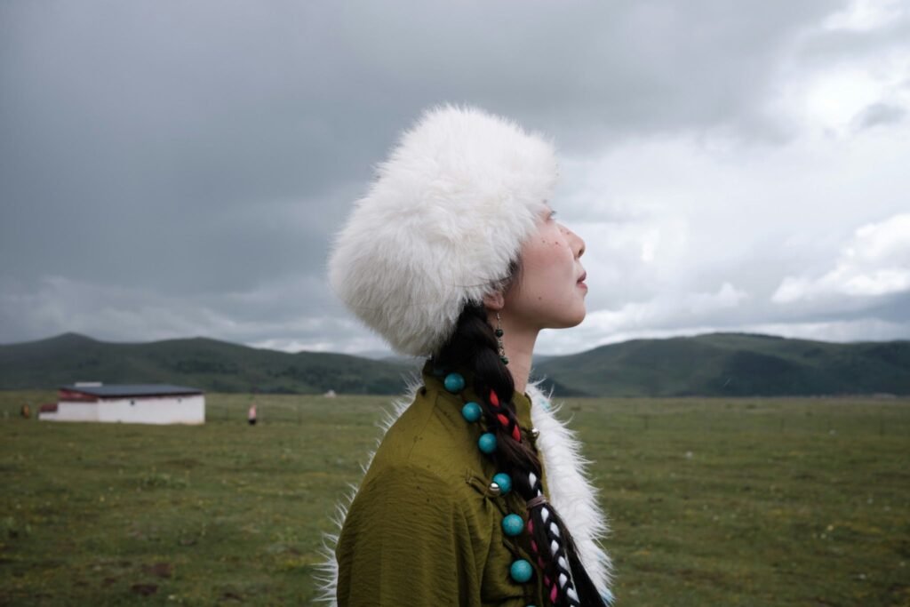 Solo travel tips - Woman in traditional clothing standing in an open grassland beneath dramatic clouds