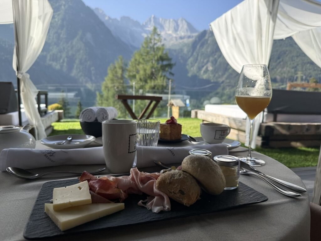 Chalet Al Foss breakfast meats and cheeses selection with mimosa cocktail and the alps in the background
