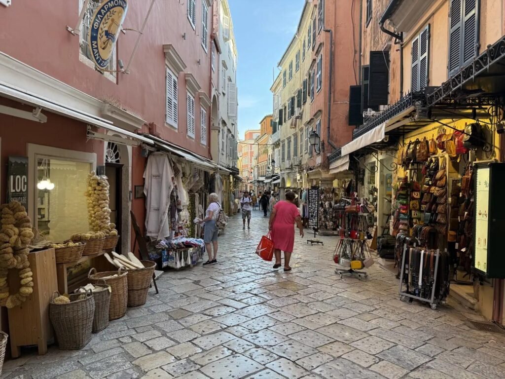 Narrow cobbled shopping street in Corfu Old Town, lined with colourful historic buildings, souvenir shops and traditional Greek products.